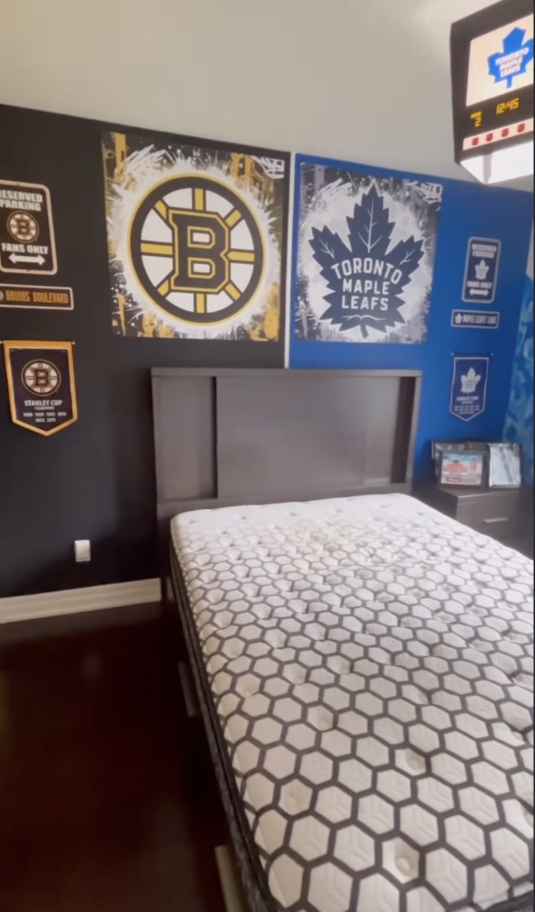 Bedroom with a navy feature wall and framed hockey banners above the bed