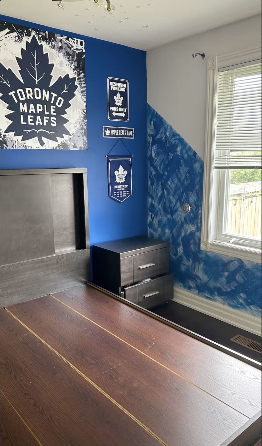Bedroom with a blue Toronto Maple Leafs feature wall and a hand-painted diagonal edge
