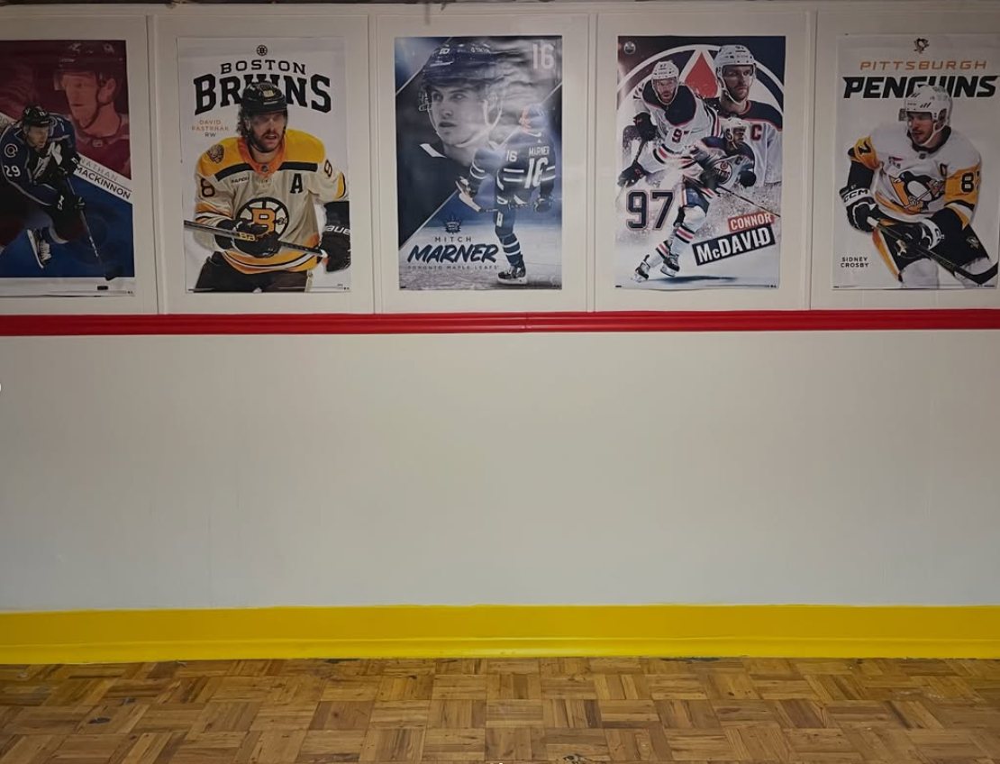 Basement room painted as hockey rink boards, with red and yellow trim and mounted hockey posters